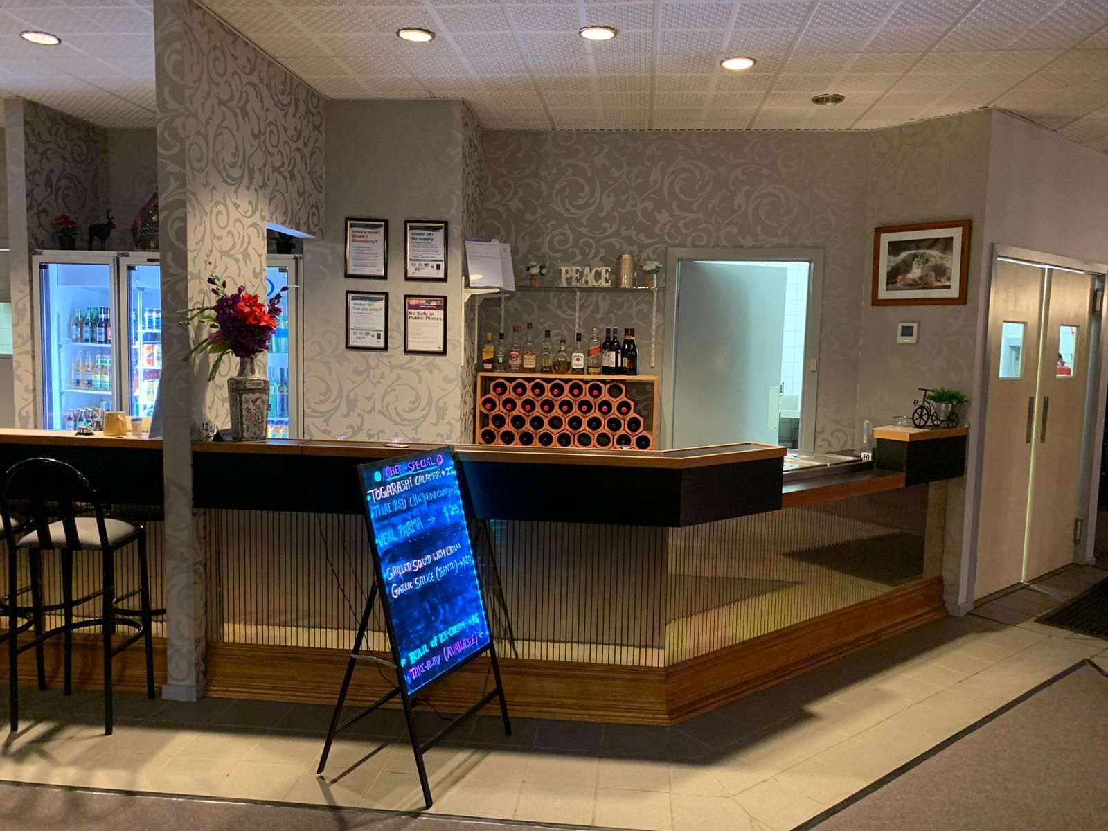 A reception area with a counter, a menu board, and a wall with framed certificates.