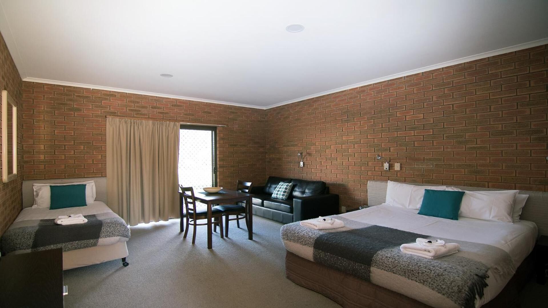 A hotel room with two beds, a dining table, and a sofa.