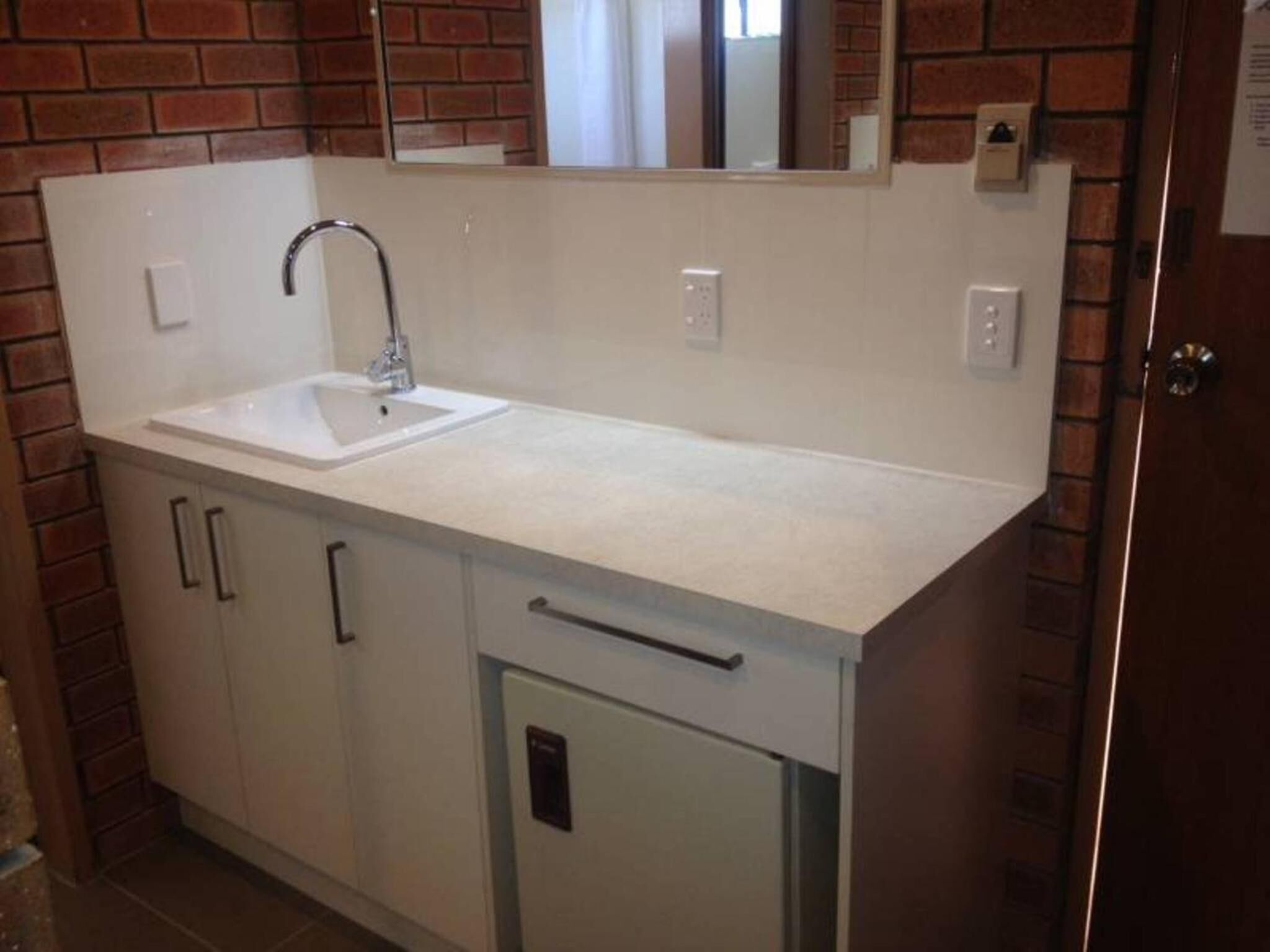 A bathroom with a white sink, a mirror above it, and a door to the right.