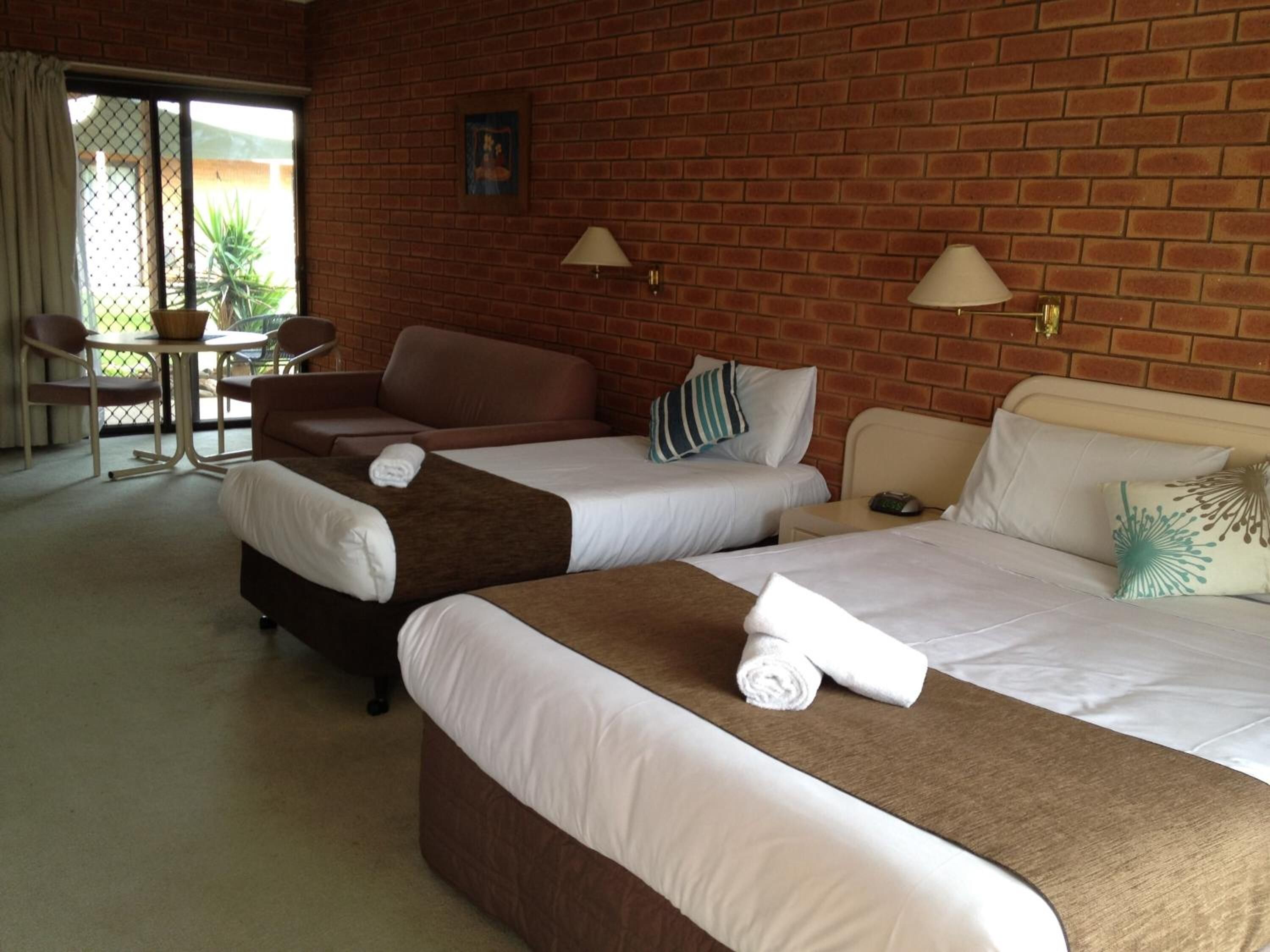 A hotel room with two beds, a small table, and a chair.