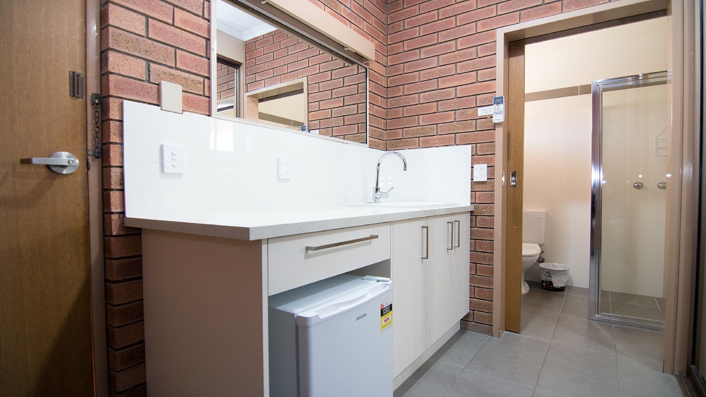 A modern bathroom with a white sink, a mirror, and a shower.