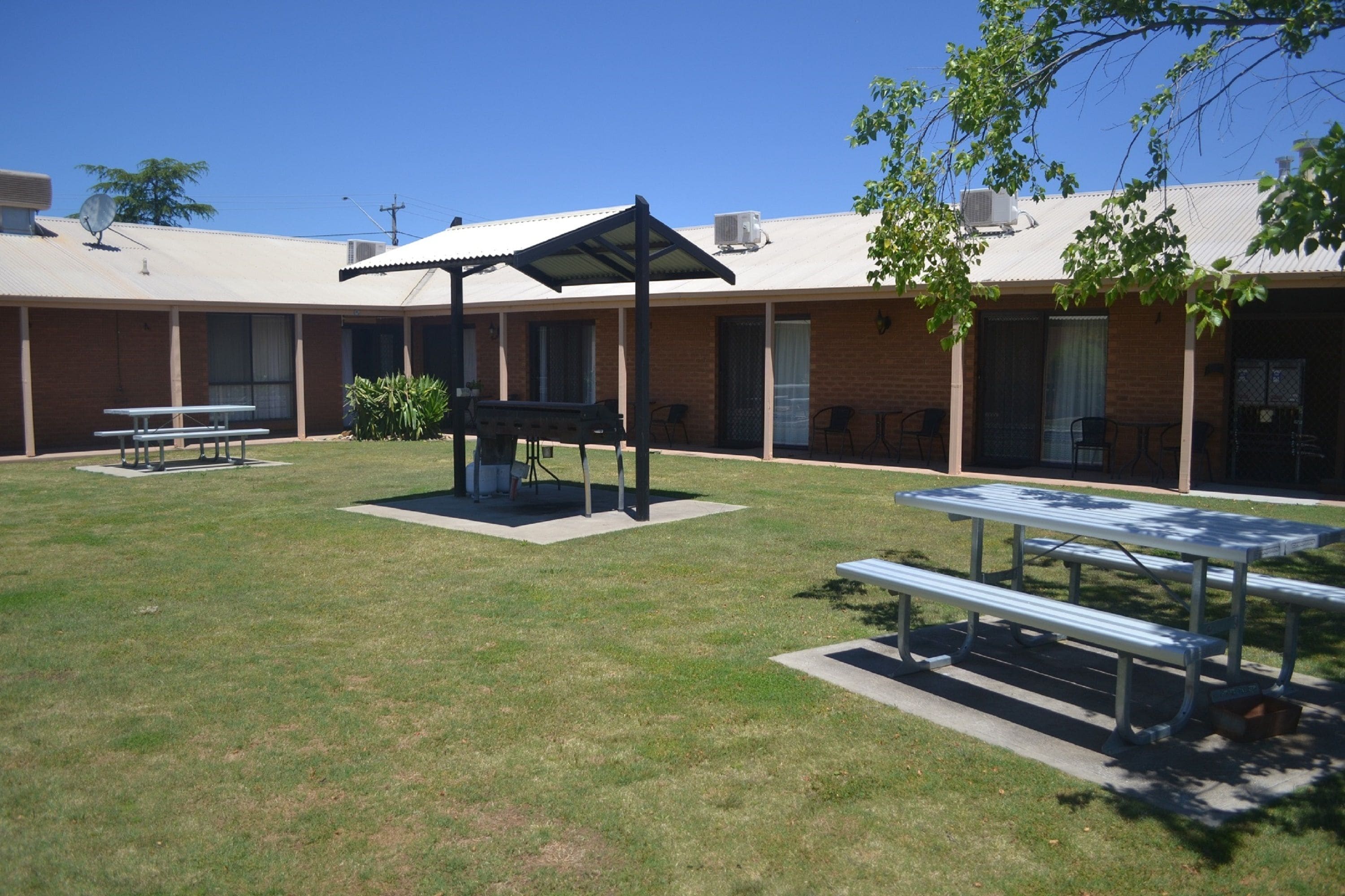 An outdoor patio area with picnic tables, a barbecue grill, and a covered seating area.