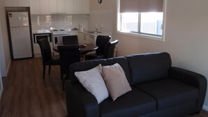 Un espacio habitable compacto con kitchenette, comedor y sala de estar con sofá y sillas.