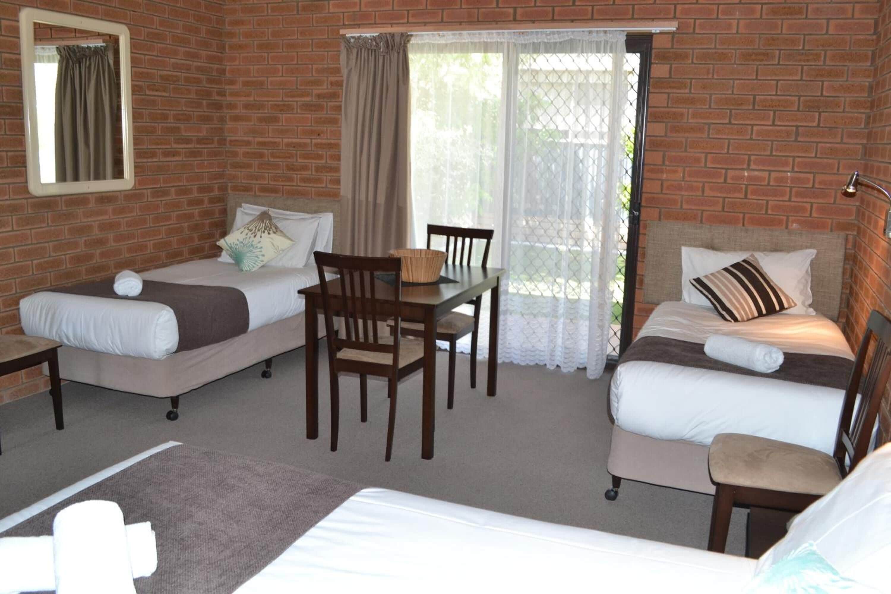 A room with two beds, a dining table, and chairs.
