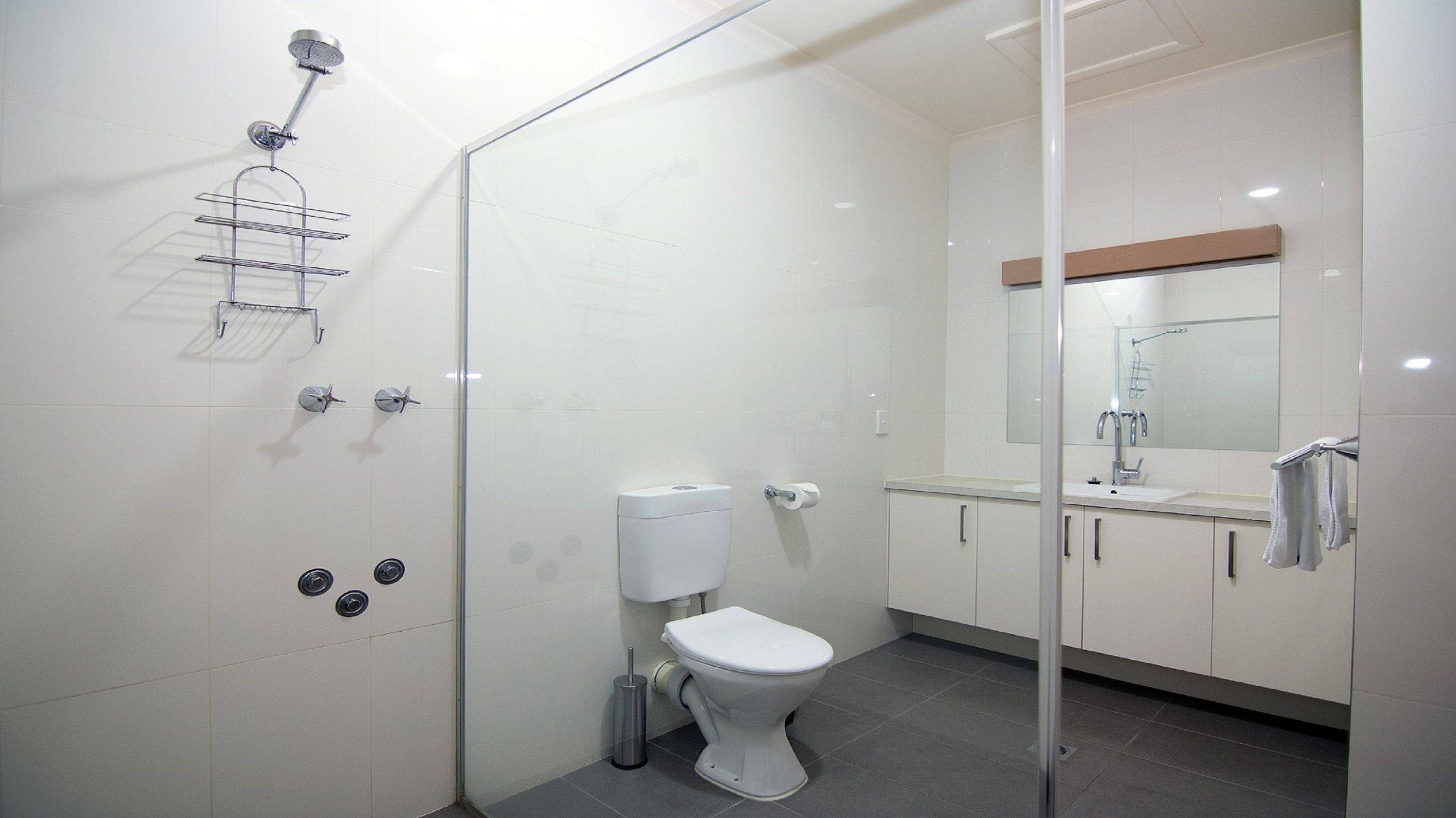 Un baño moderno con cabina de ducha de vidrio, inodoro, lavabo y espejo.