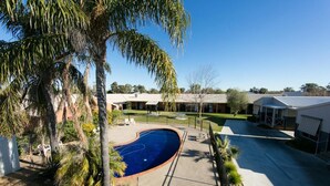 Zona residencial con piscina, palmeras y casas.