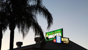 A motel sign with a green and yellow signboard, a blue signboard, and a black signboard. - The Jolly Swagman Motor Inn (Goondiwindi)