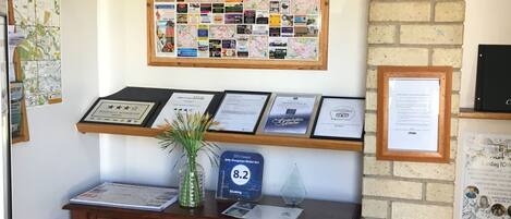 A reception desk with a framed map, a bulletin board with various notices, and a framed award certificate.