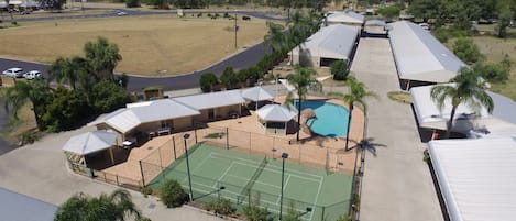 A large building with multiple tennis courts, a swimming pool, and several covered areas.