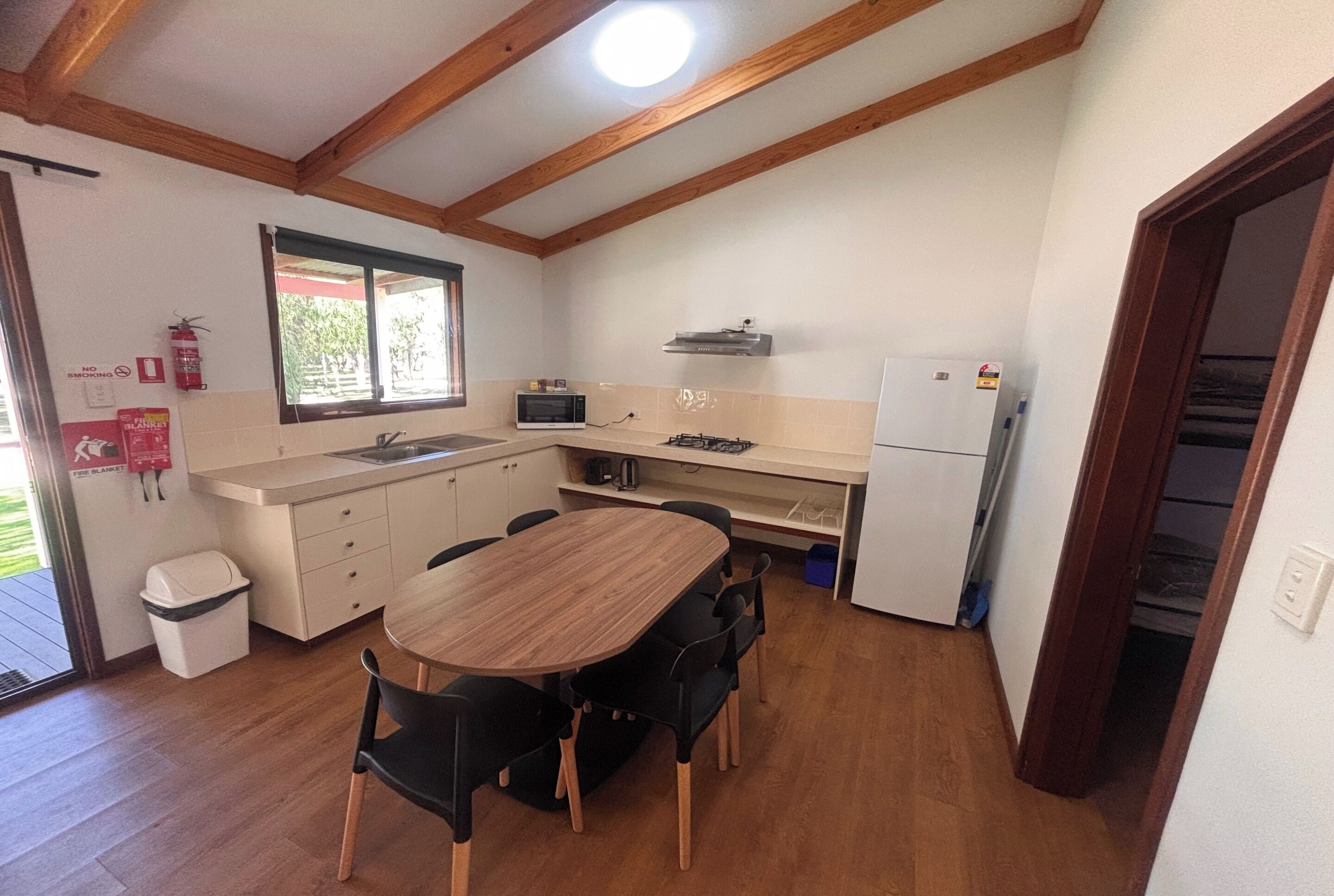 A compact kitchen with a wooden table, chairs, a microwave, a stove, and a refrigerator.