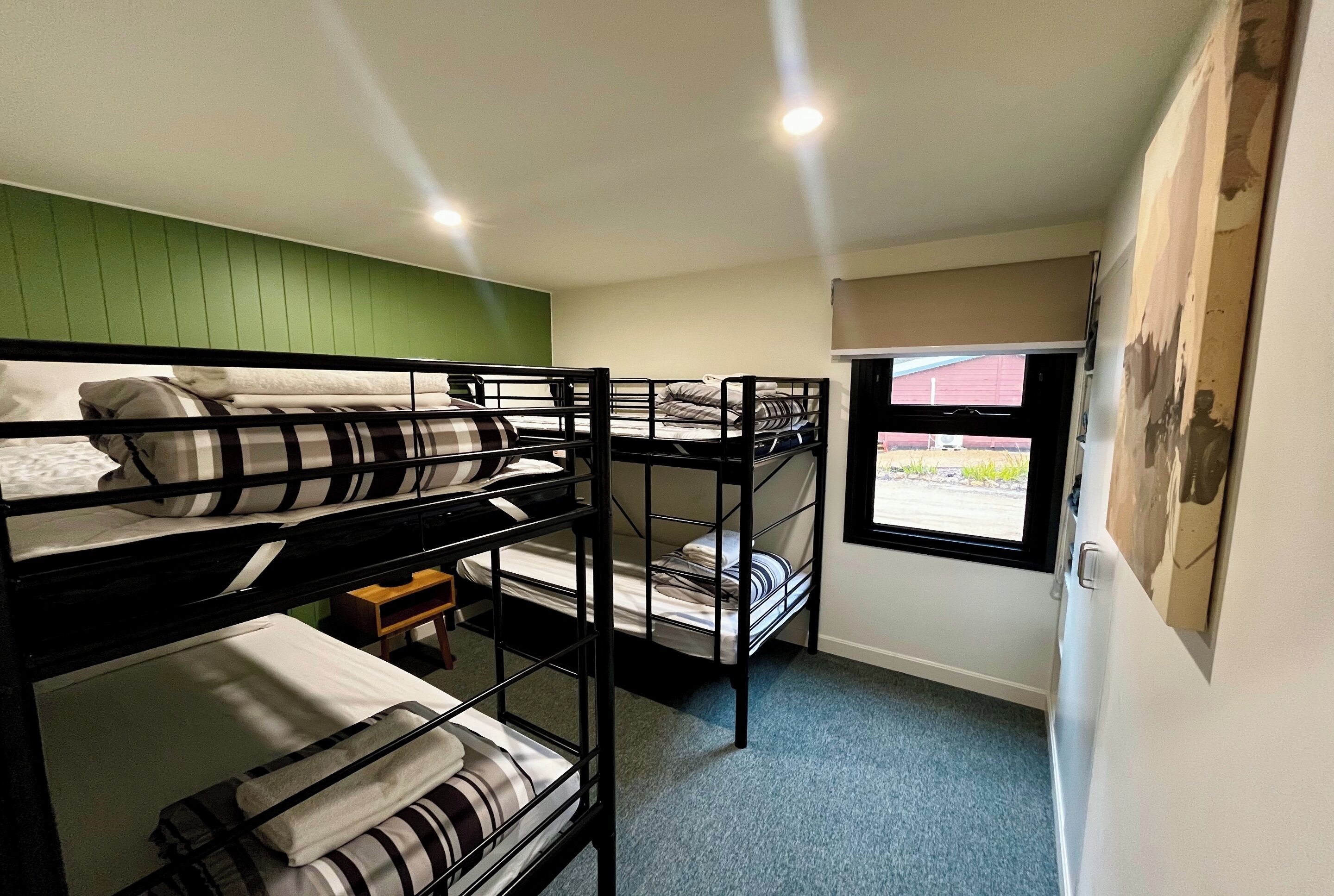 A bunk bed room with a green wall, a window, and a door.