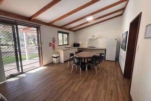 Una cocina compacta con comedor, vigas de madera en el techo y vistas a través de un ventanal.