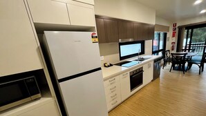 Une cuisine moderne équipée d’un réfrigérateur, d’un four à micro-ondes, d’un évier et de meubles de rangement en bois.