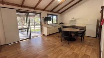 A kitchen with a dining table, chairs, a microwave, and a refrigerator.