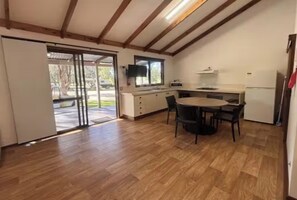 Una cocina con una mesa de comedor, sillas, microondas y refrigerador.