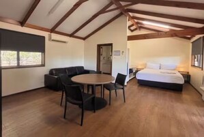 Una habitación con una cama, una mesa redonda con sillas, un sofá y una ventana.