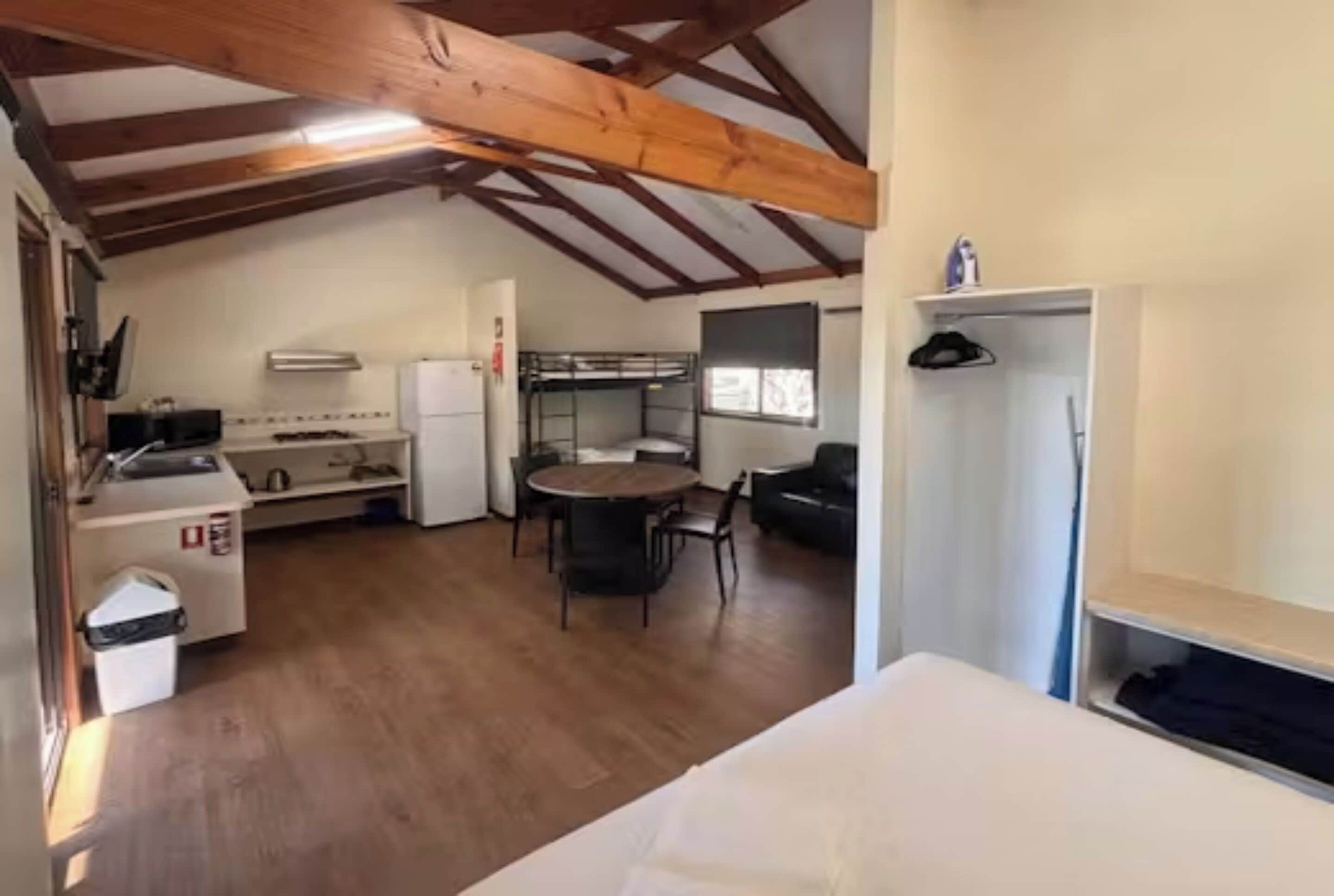 A compact room with a bed, kitchenette, and a dining area.