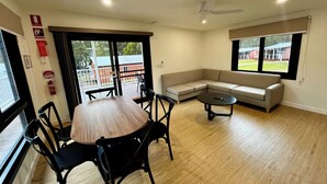 Un salon moderne avec une table à manger en bois, des chaises noires, un canapé beige et une petite table basse.