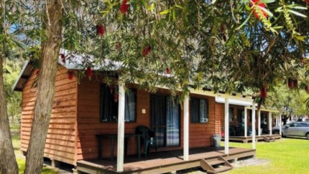 Une cabane en bois avec une véranda, une table et une chaise à l’extérieur.