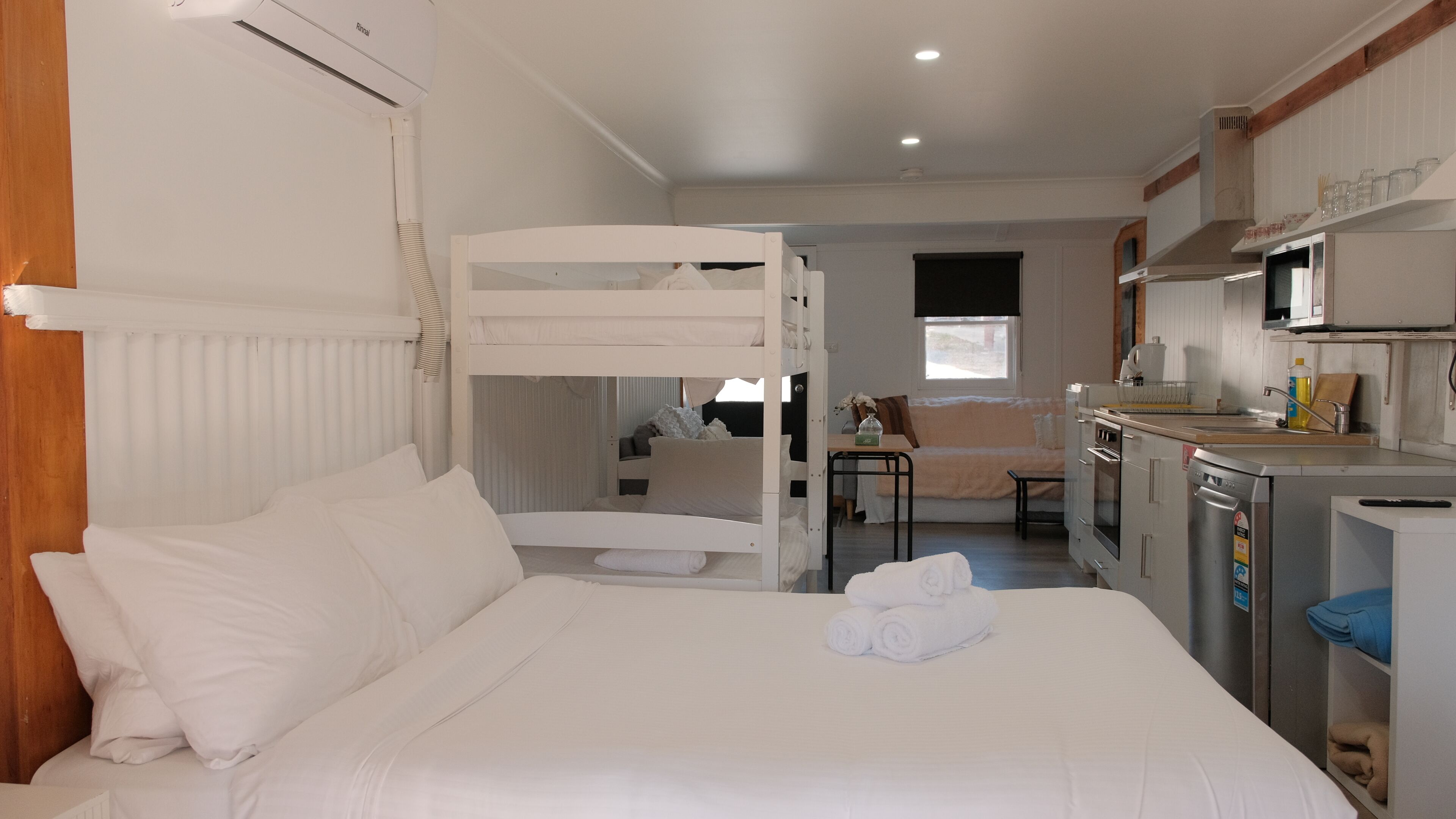 Ein Zimmer mit Stockbetten, einer Küchenzeile und einem Essbereich.