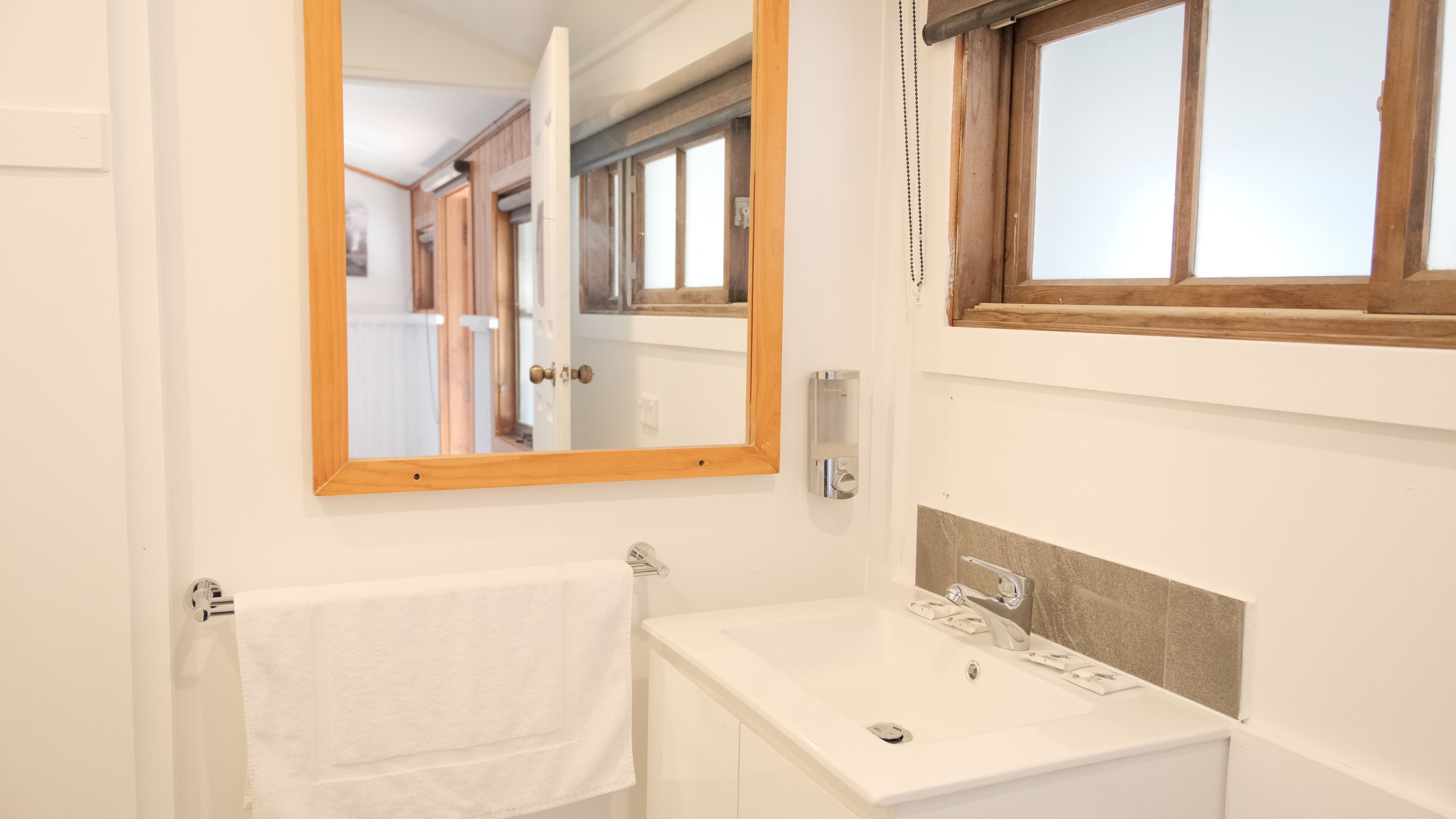 Une salle de bain avec un lavabo blanc, un miroir et un porte-serviettes.