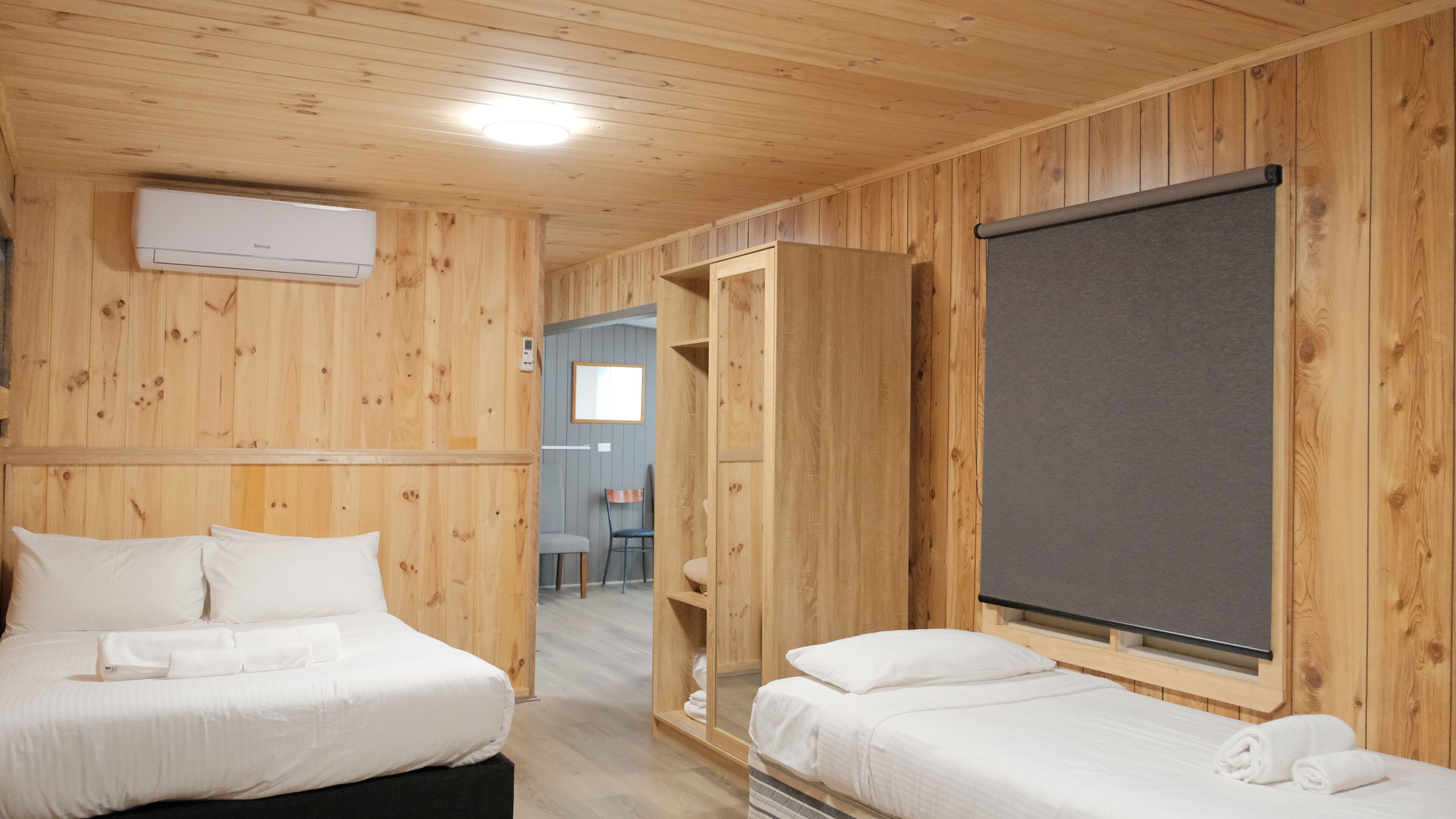A wooden room with two beds, a mirror, and a window.
