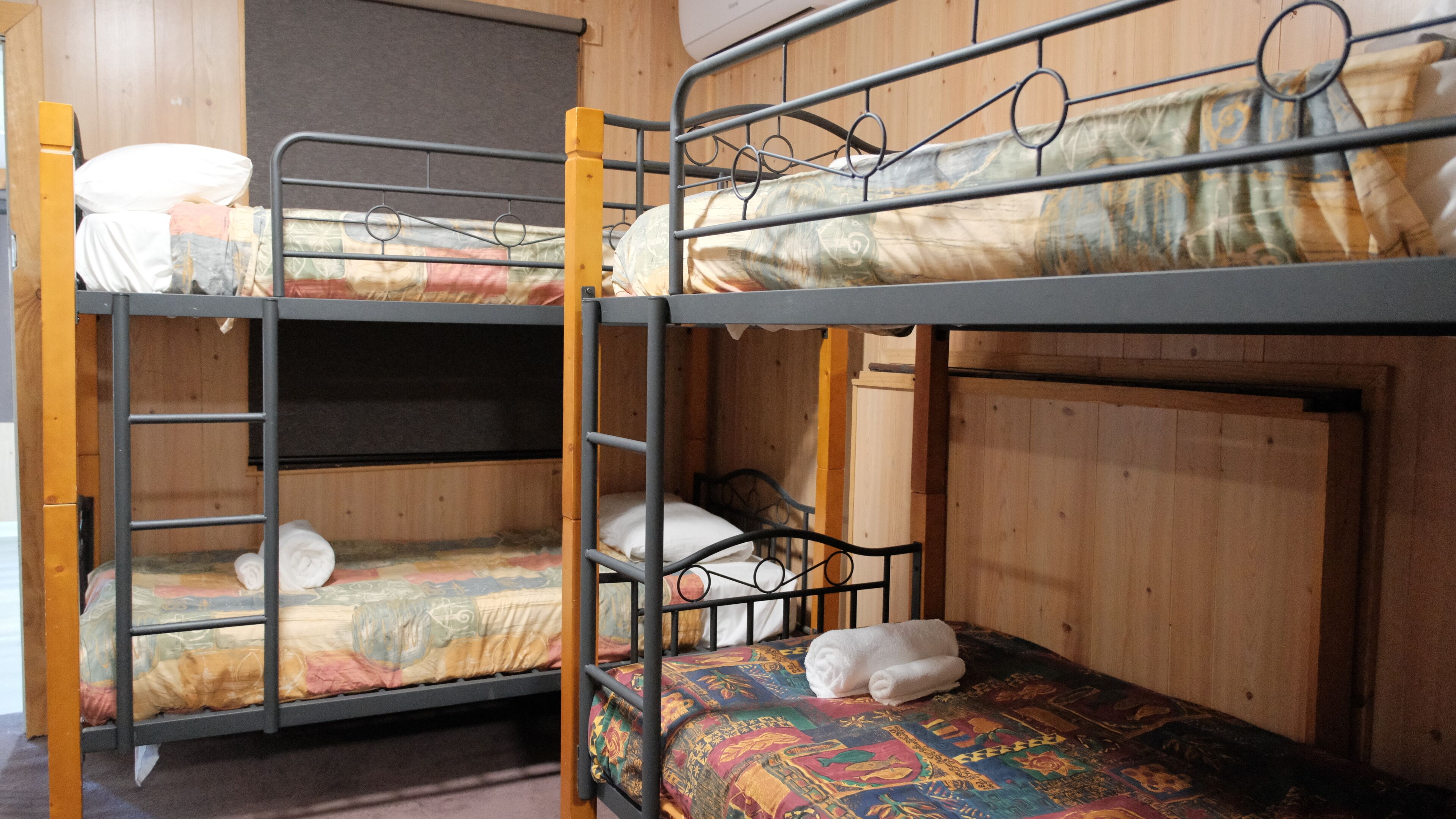 Een slaapkamer met een stapelbed, een houten hoofdbord en een bed met een decoratieve spreideken.