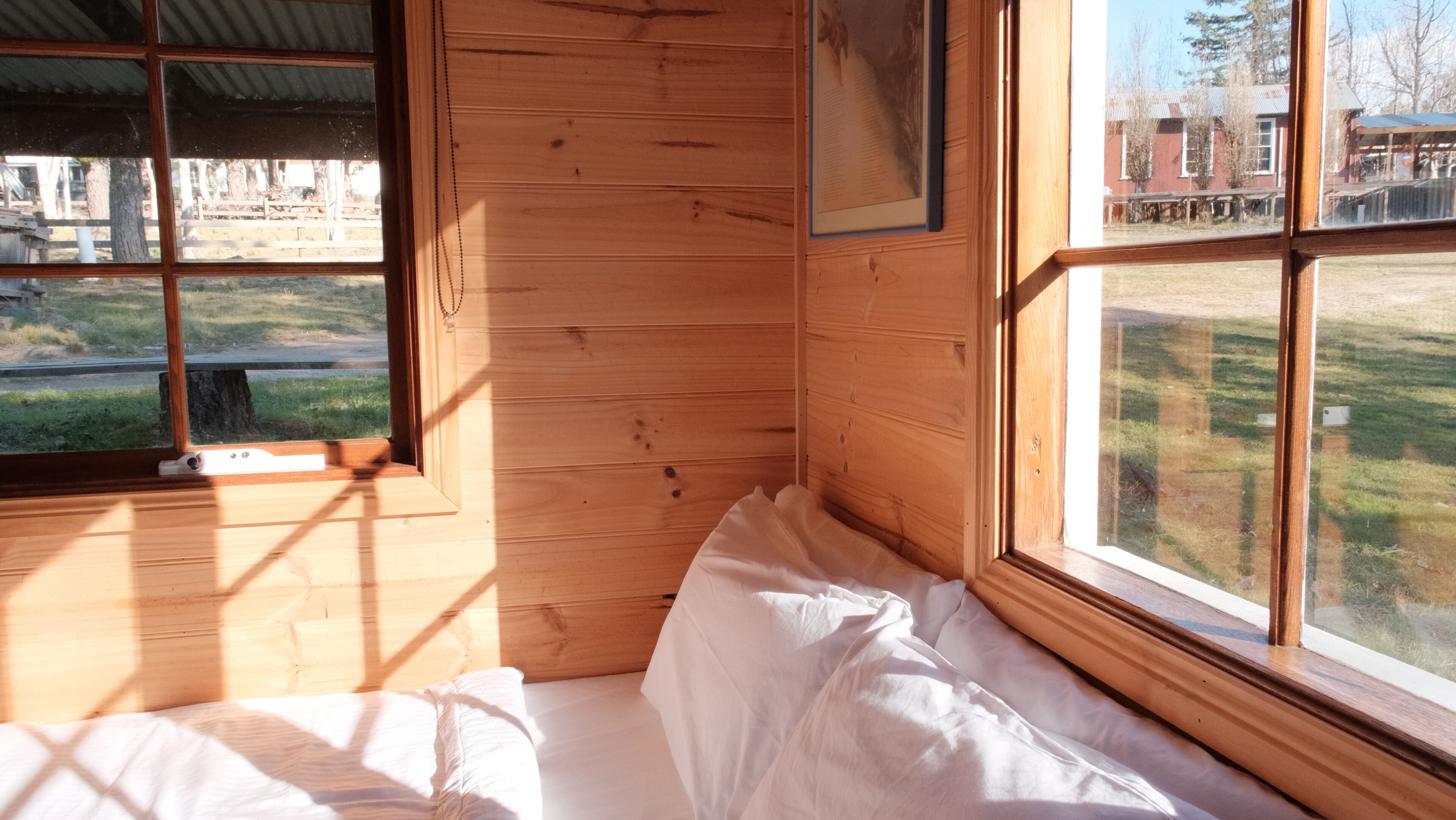 Une pièce de cabane en bois comprenant un lit, une fenêtre et un tableau encadré accroché au mur.
