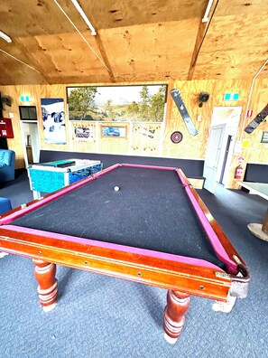 A pool table with a black felt surface and a wooden frame with pink accents.