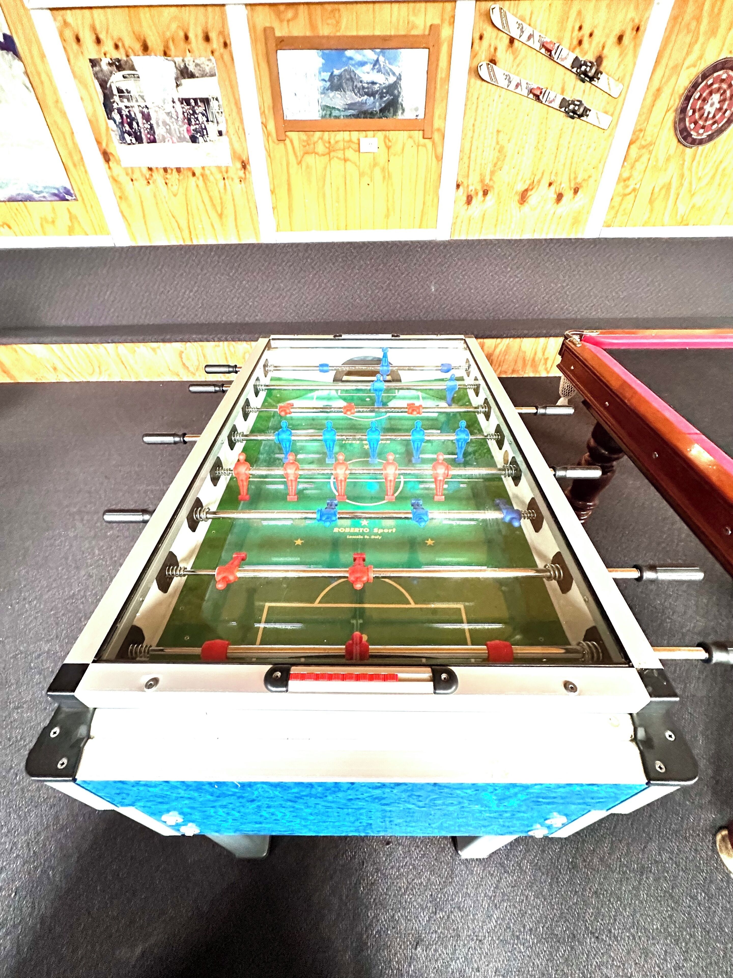 A foosball table with a wooden backdrop and framed pictures.