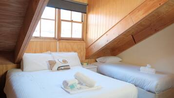 A room with two beds, a window, and wooden beams.