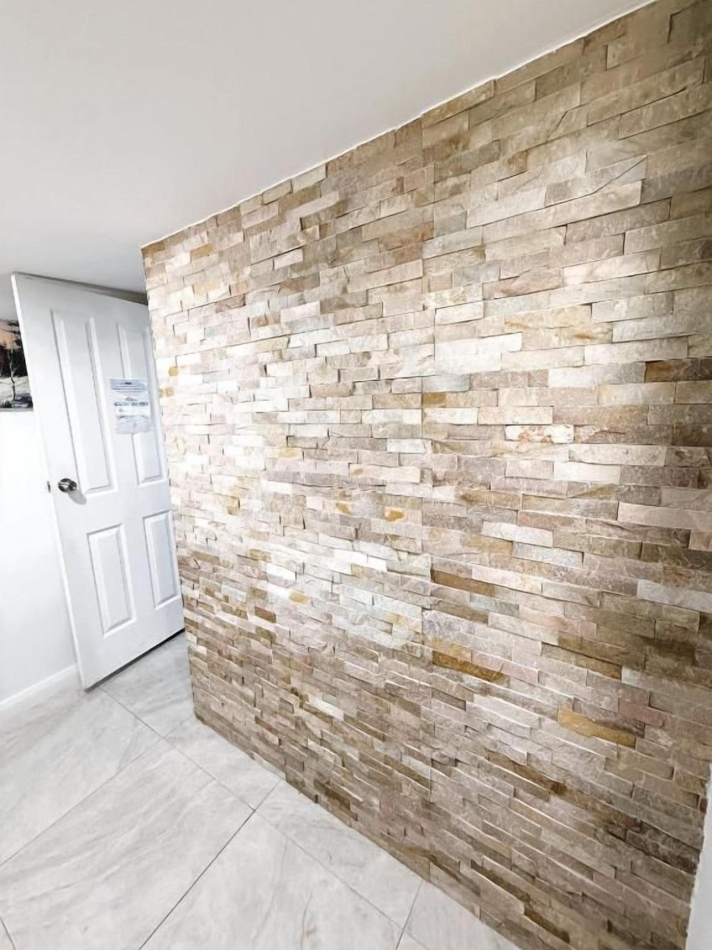 A hallway with a textured stone wall and a white door.