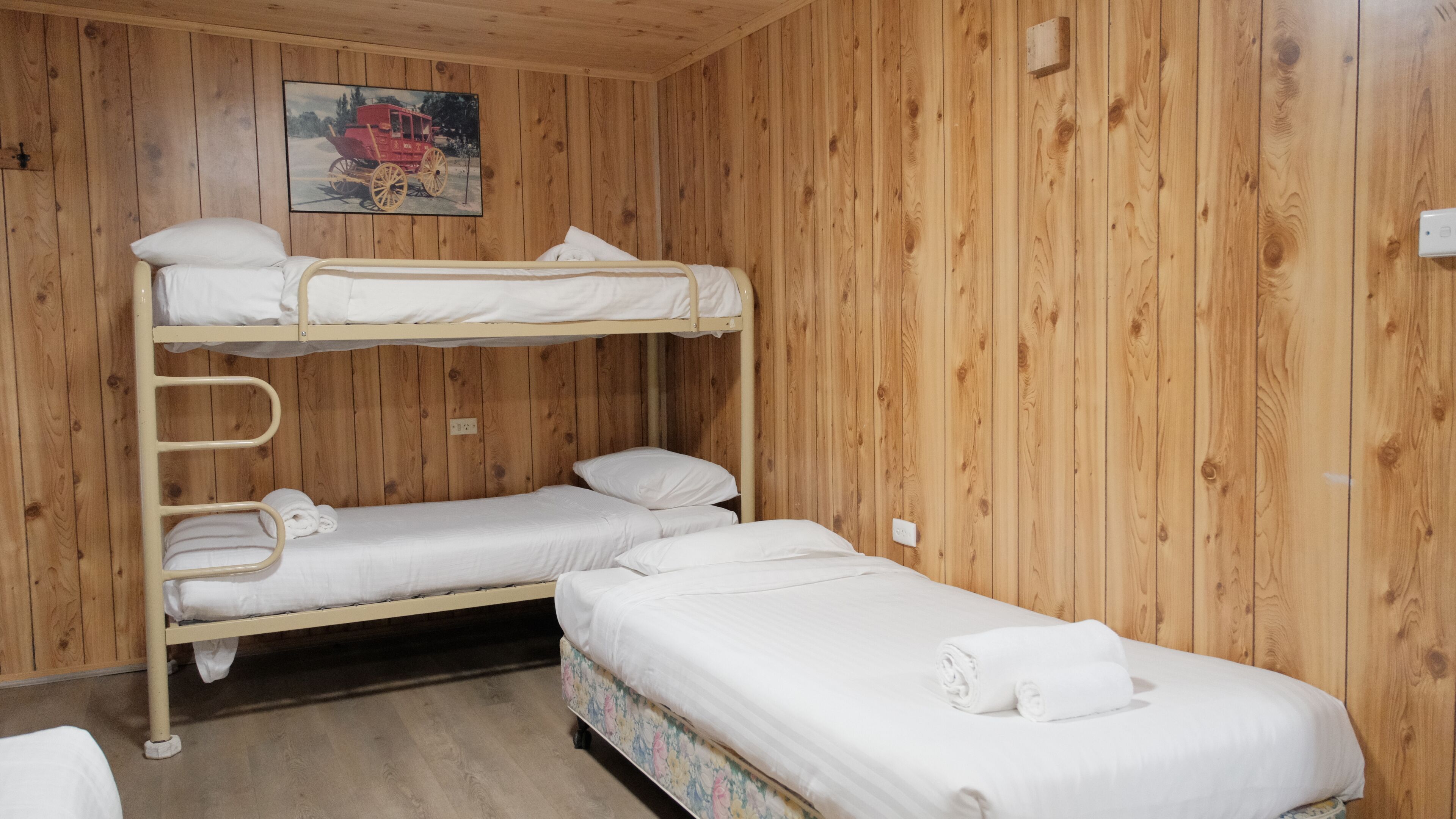 A bunk bed room with wooden walls, a painting, and a power outlet.