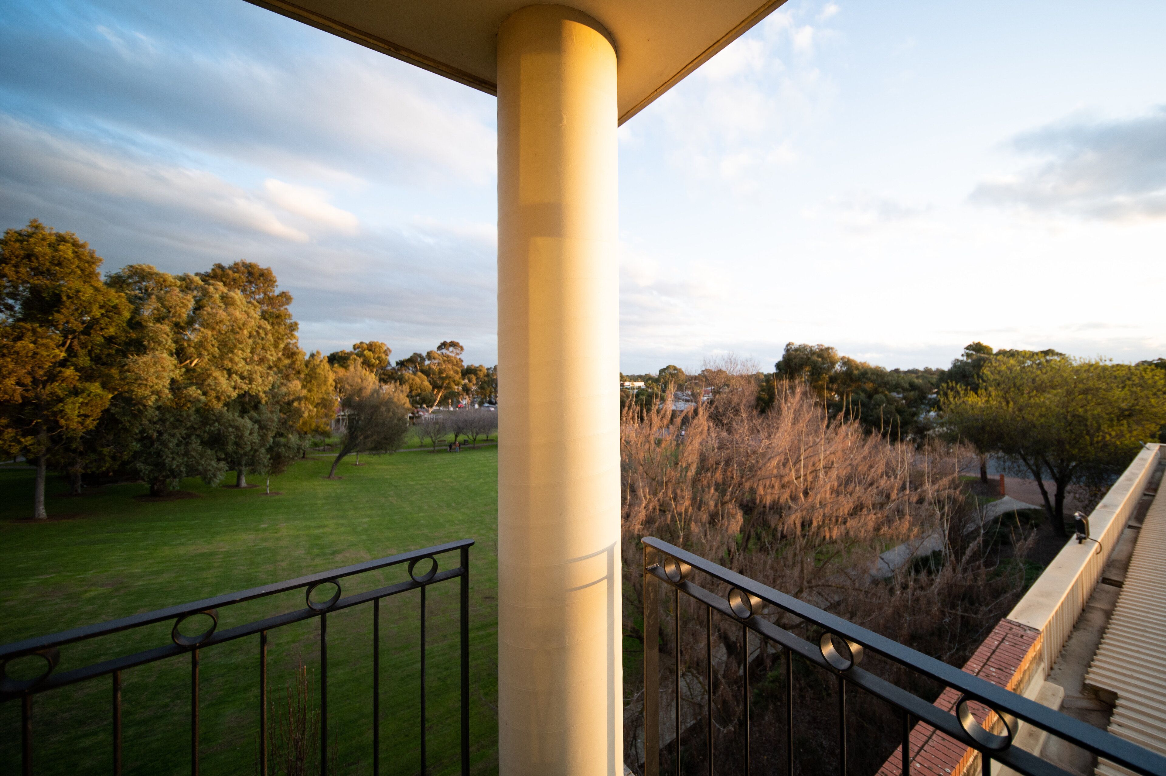 A balcony with a view of a park and trees.