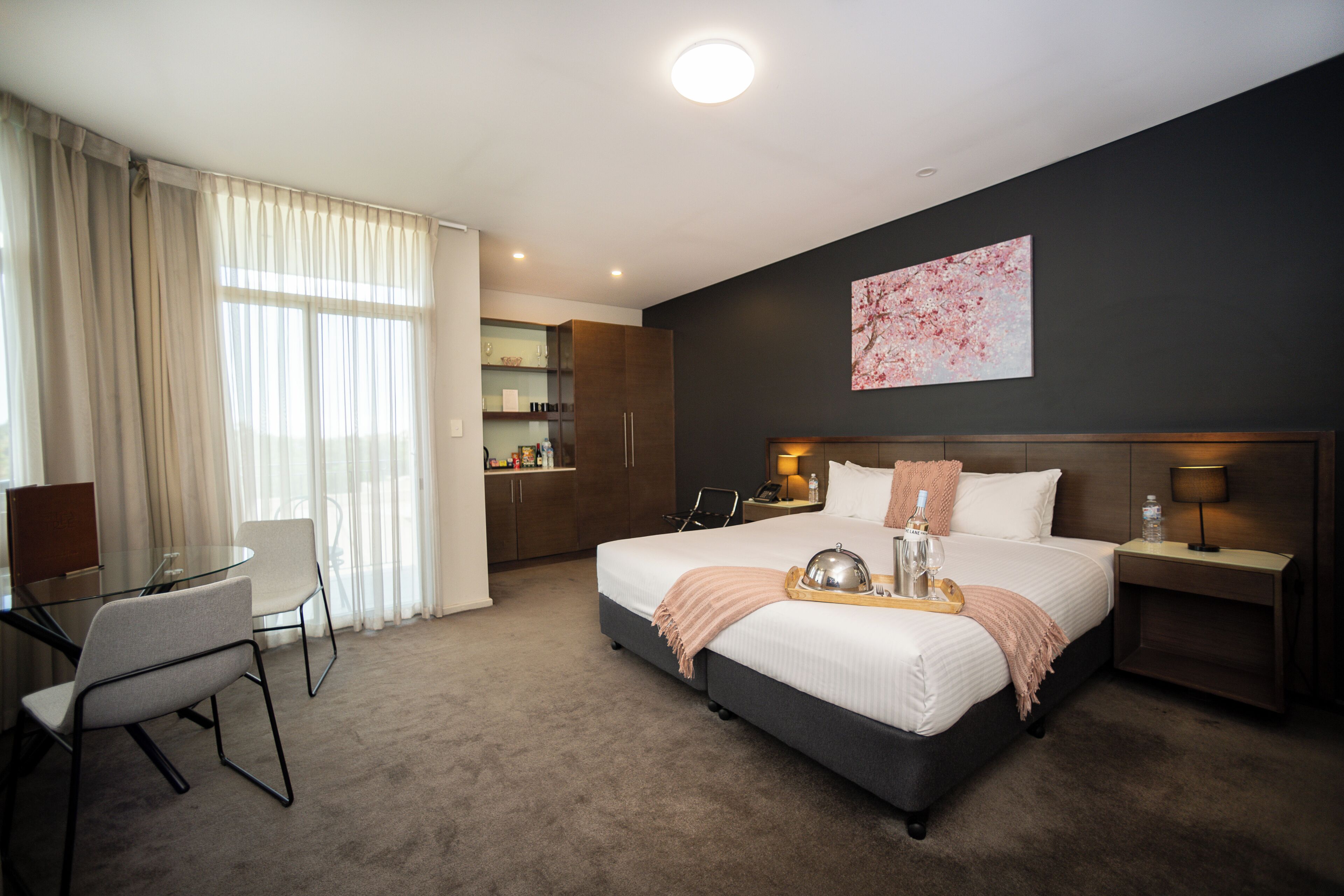 Ett hotellrum med en säng, sängbord, ett skrivbord och en stol.