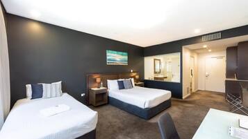 A hotel room with two beds, a desk, and a mirror.