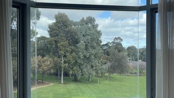A room with a large bay window offering a view of a grassy area and trees.