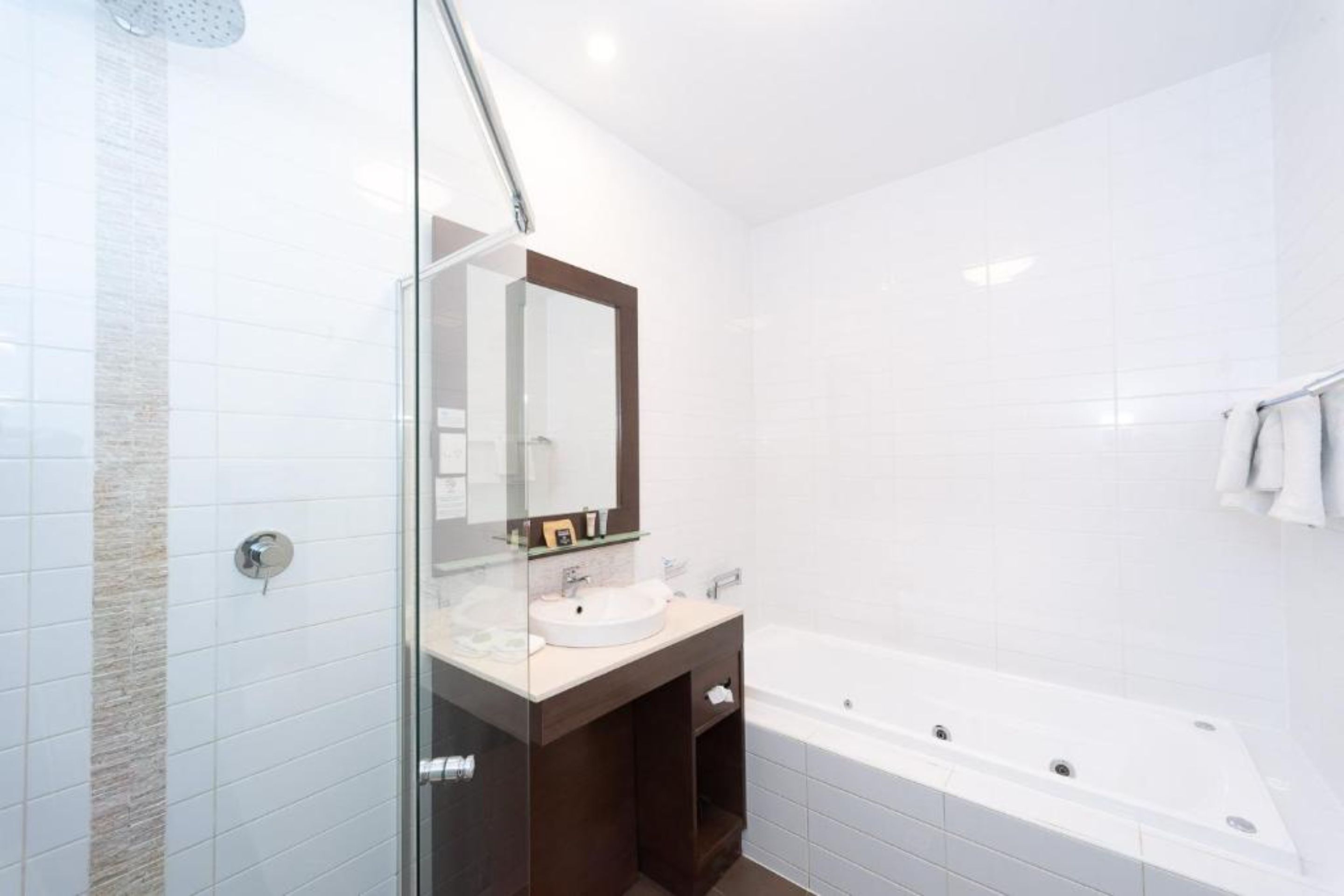 A modern bathroom with a glass shower enclosure, a vanity with a sink, and a large bathtub.