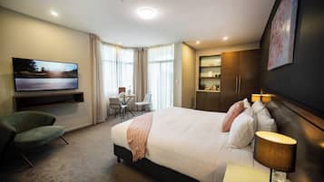 Una habitación de hotel con cama, televisión, escritorio y silla.