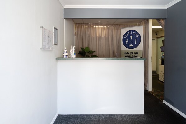 A reception desk with a sign for the Tradie Club. There are two bottles and a potted plant on the counter. - Browns Plains Hotel (Browns Plains)