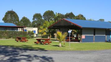 Um camping com duas cabanas, mesas de piquenique e um céu claro.
