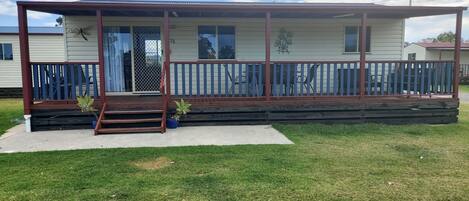 A single-story mobile home with a covered porch, a small front door, and a visible number "25" on the door.