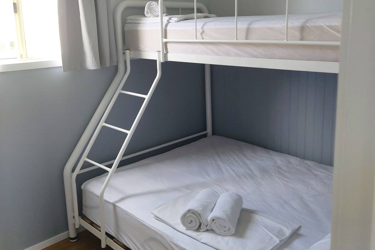 A bunk bed room with a window and curtains.