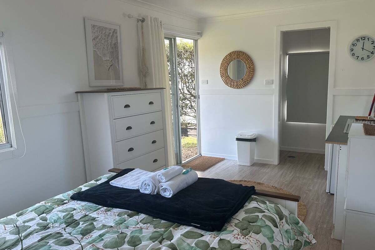 A bedroom with a bed, a dresser, a mirror, and a door leading to a balcony.