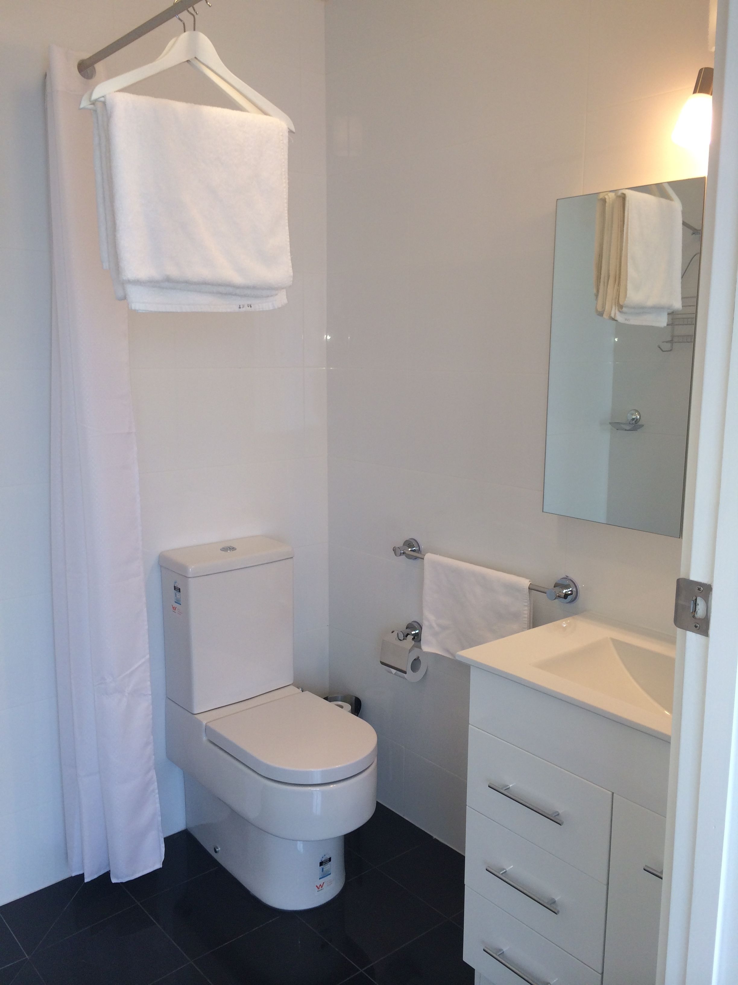 Un baño moderno con inodoro, lavamanos y espejo.