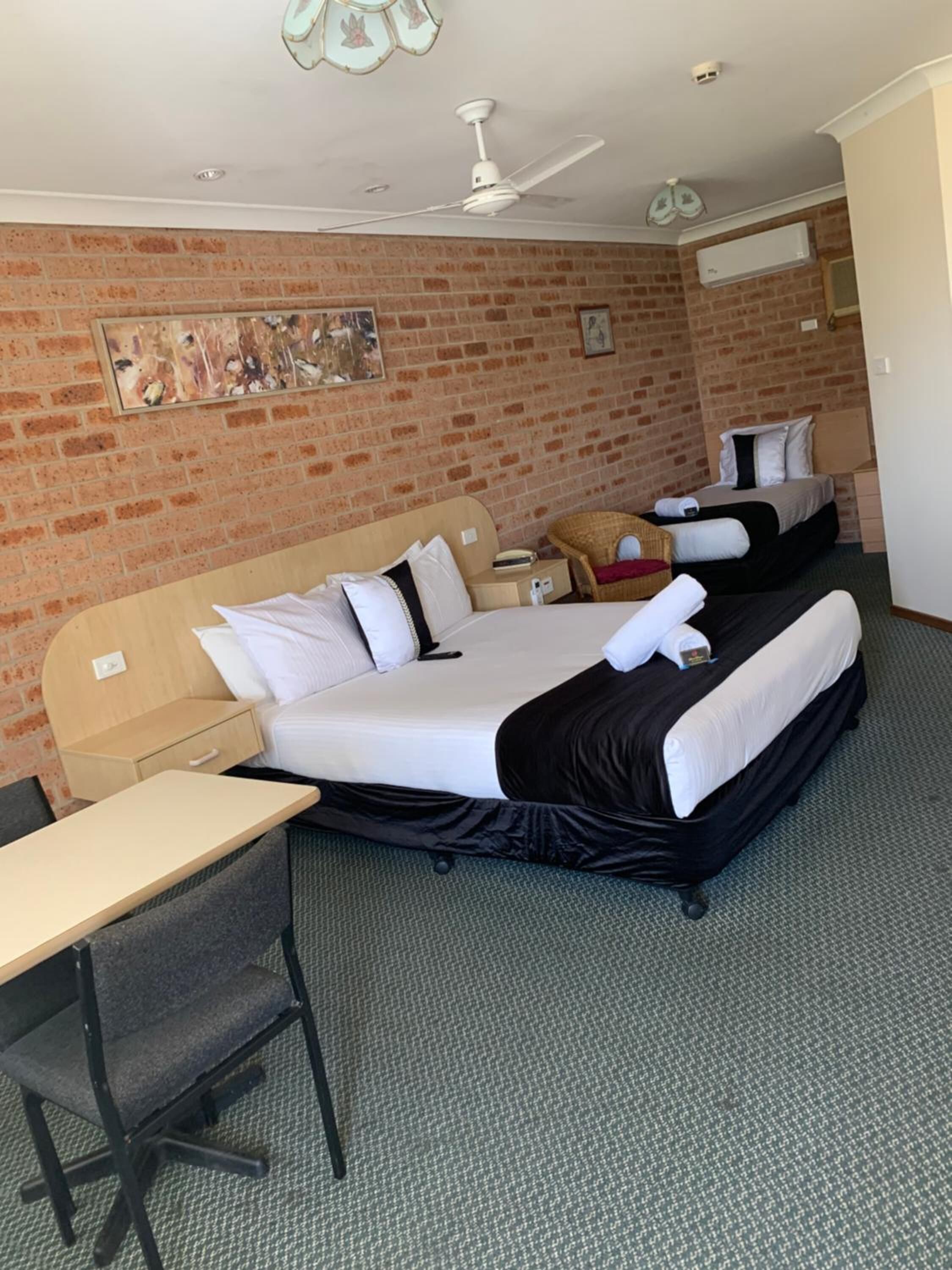 A hotel room with two beds, a desk, and a chair.