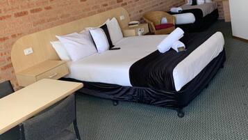 A hotel room with two beds, a desk, and a chair.