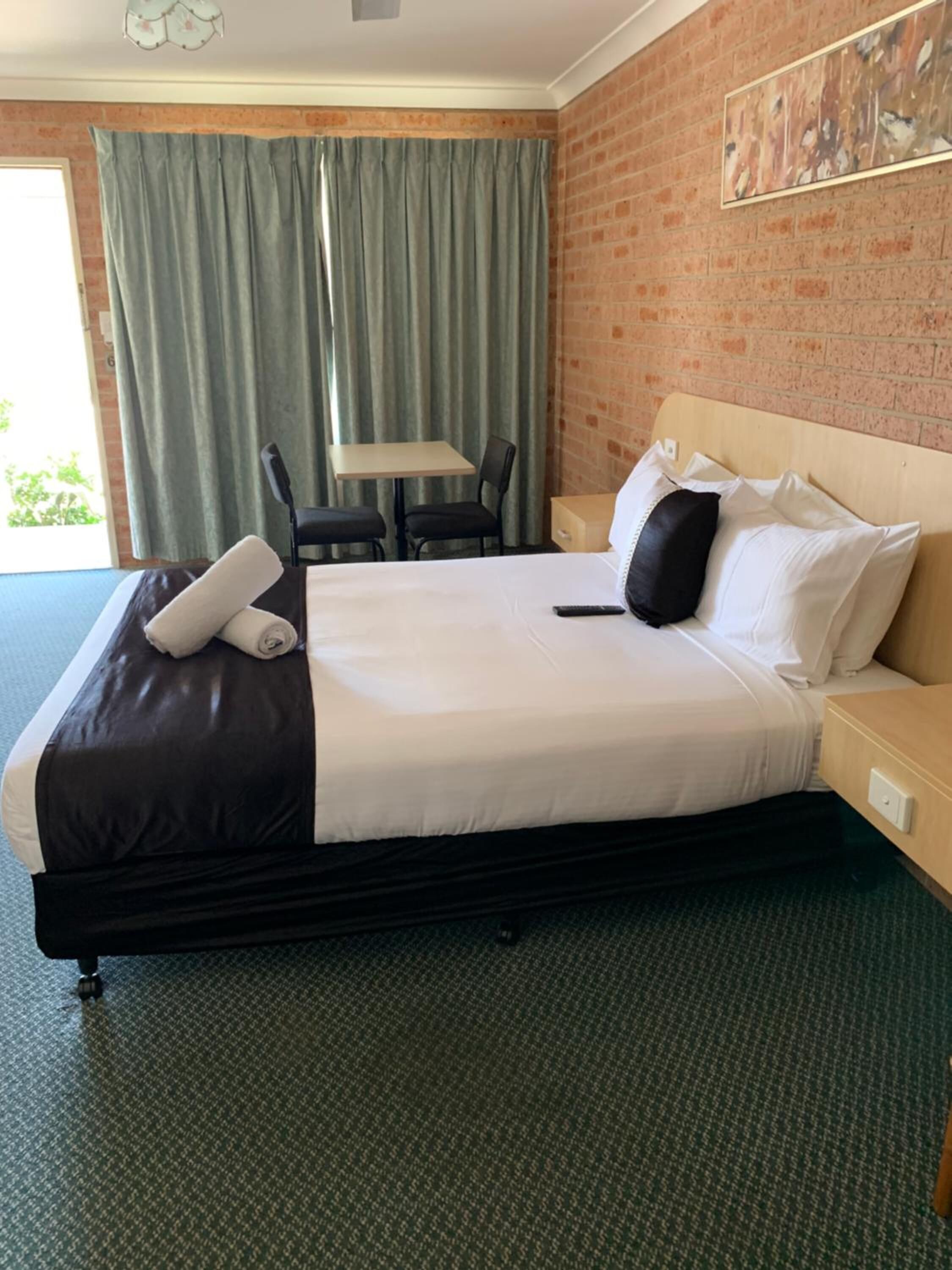 Una camera d'albergo con un letto grande, una scrivania, una sedia e una finestra con tende.