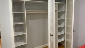 A walk-in closet with multiple shelves and hanging space. - Branxton House Motel, Hunter Valley (Branxton)