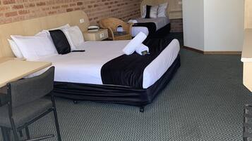 Habitación de hotel con una cama grande, un escritorio, una silla, un armario y un ventilador de techo.